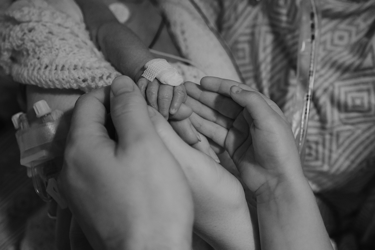 family-holding-the-hand-of-trisomy-18-baby